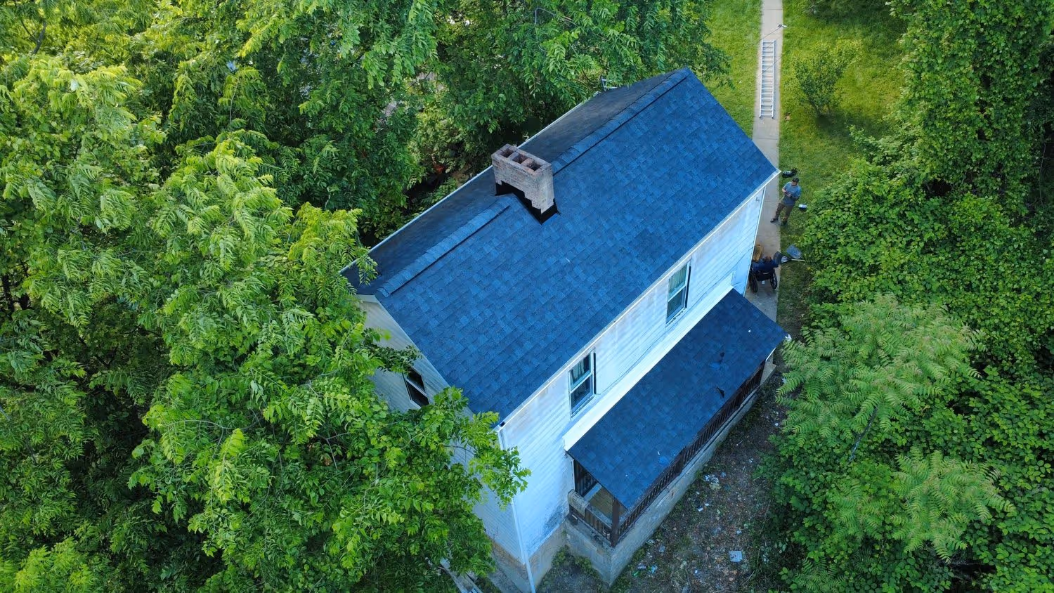 Aerial view of the new roof at E. Lemington, fresh shingles and a crew member on the walk below